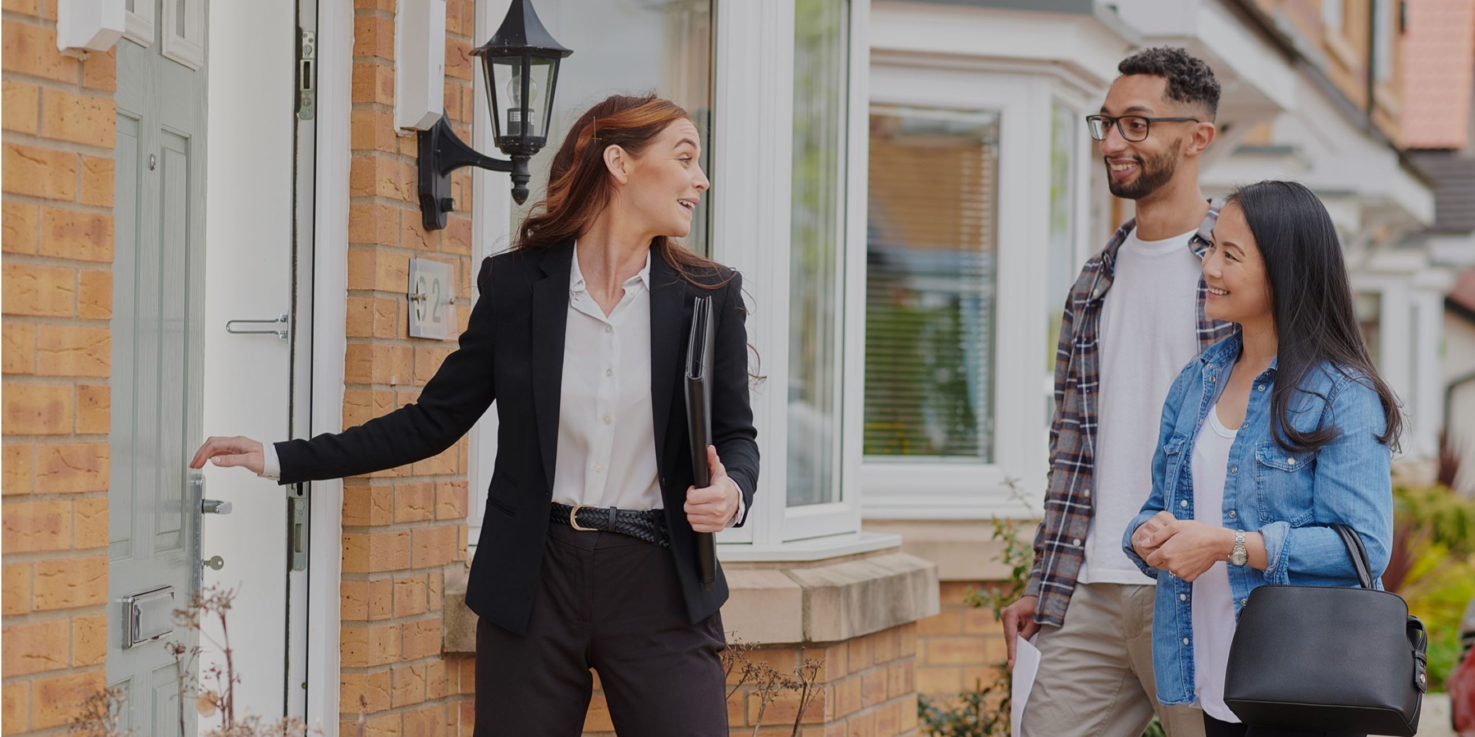 Female real estate agent outside front door with couple
