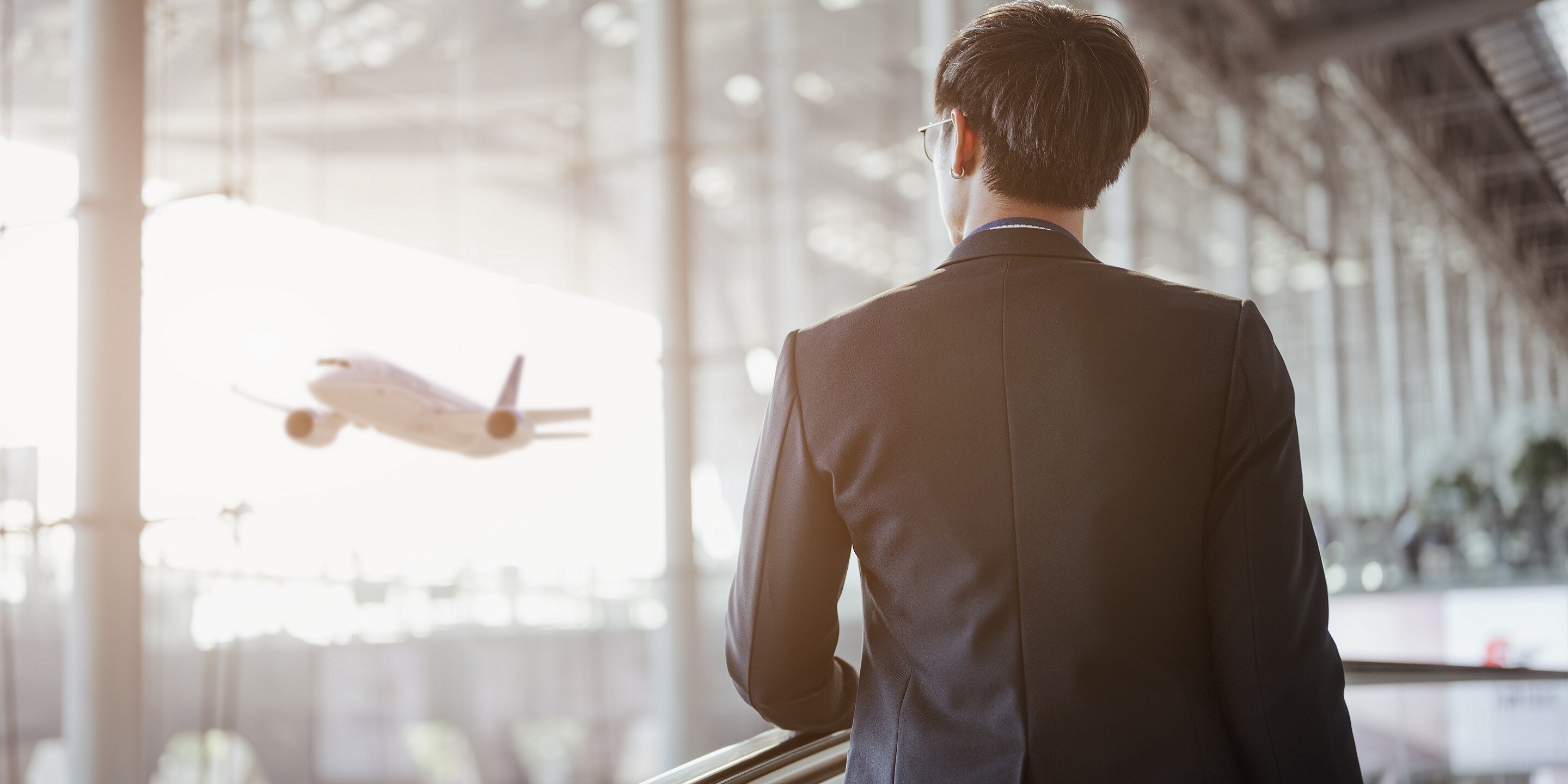 Businessman moving to terminal gate by escalator for check in boarding with luggage at the airport.